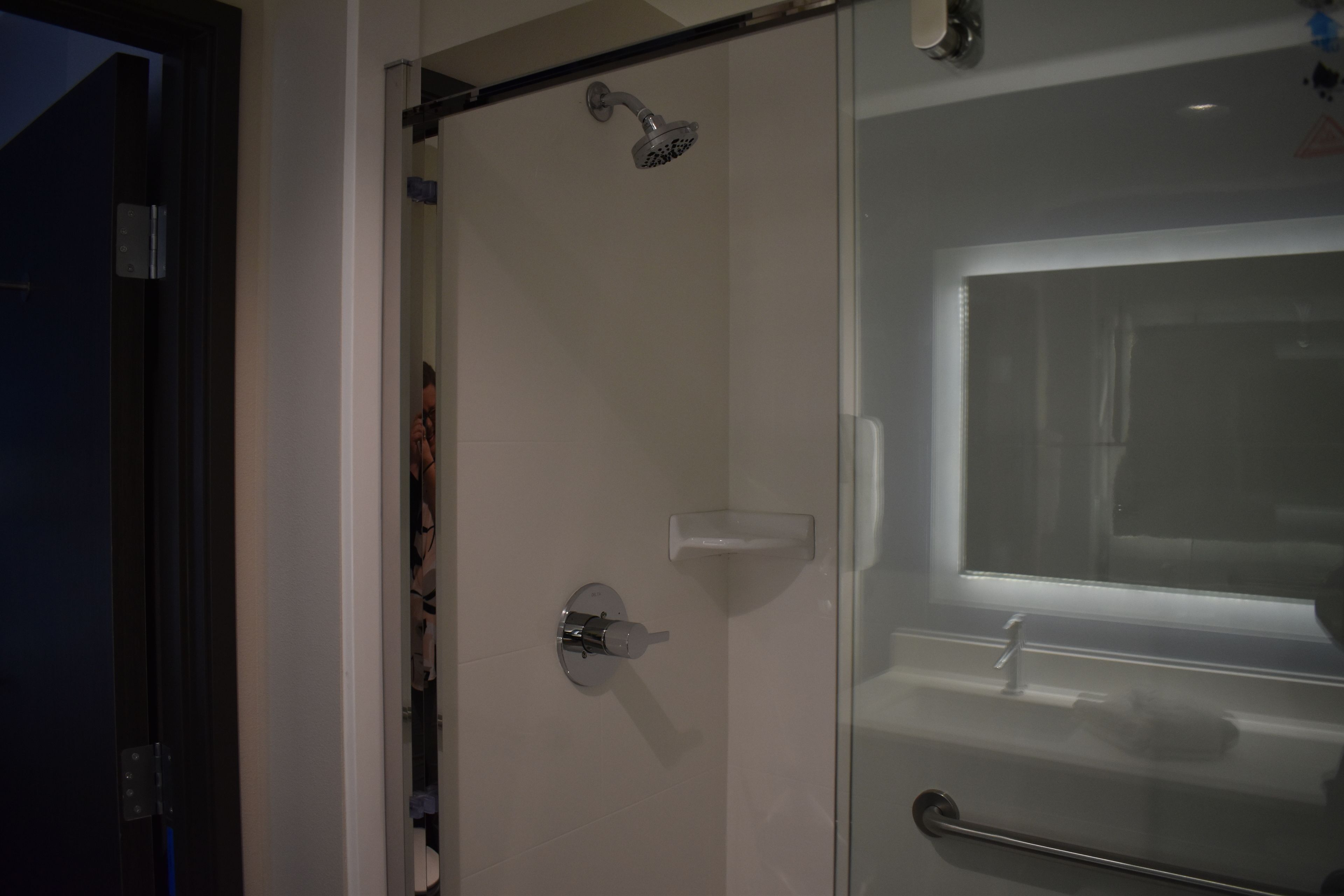 A glass shower enclosure with a handheld showerhead and a glass door.
