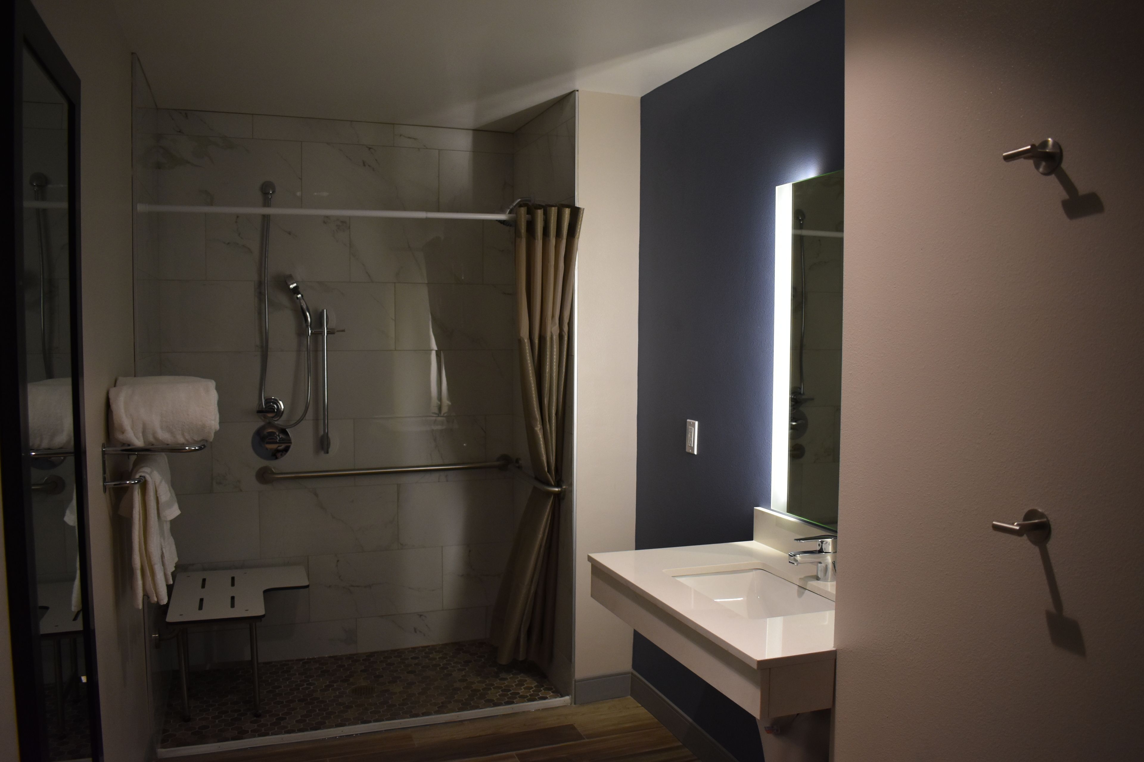 A modern bathroom with a walk-in shower, a glass shower enclosure, a white sink, and a mirror.