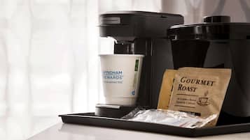 Une machine à café, un gobelet jetable et un sachet de café sur un plateau.