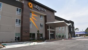 Hotel La Quinta con un diseño moderno, que presenta un destacado logo de sol y una entrada cubierta.