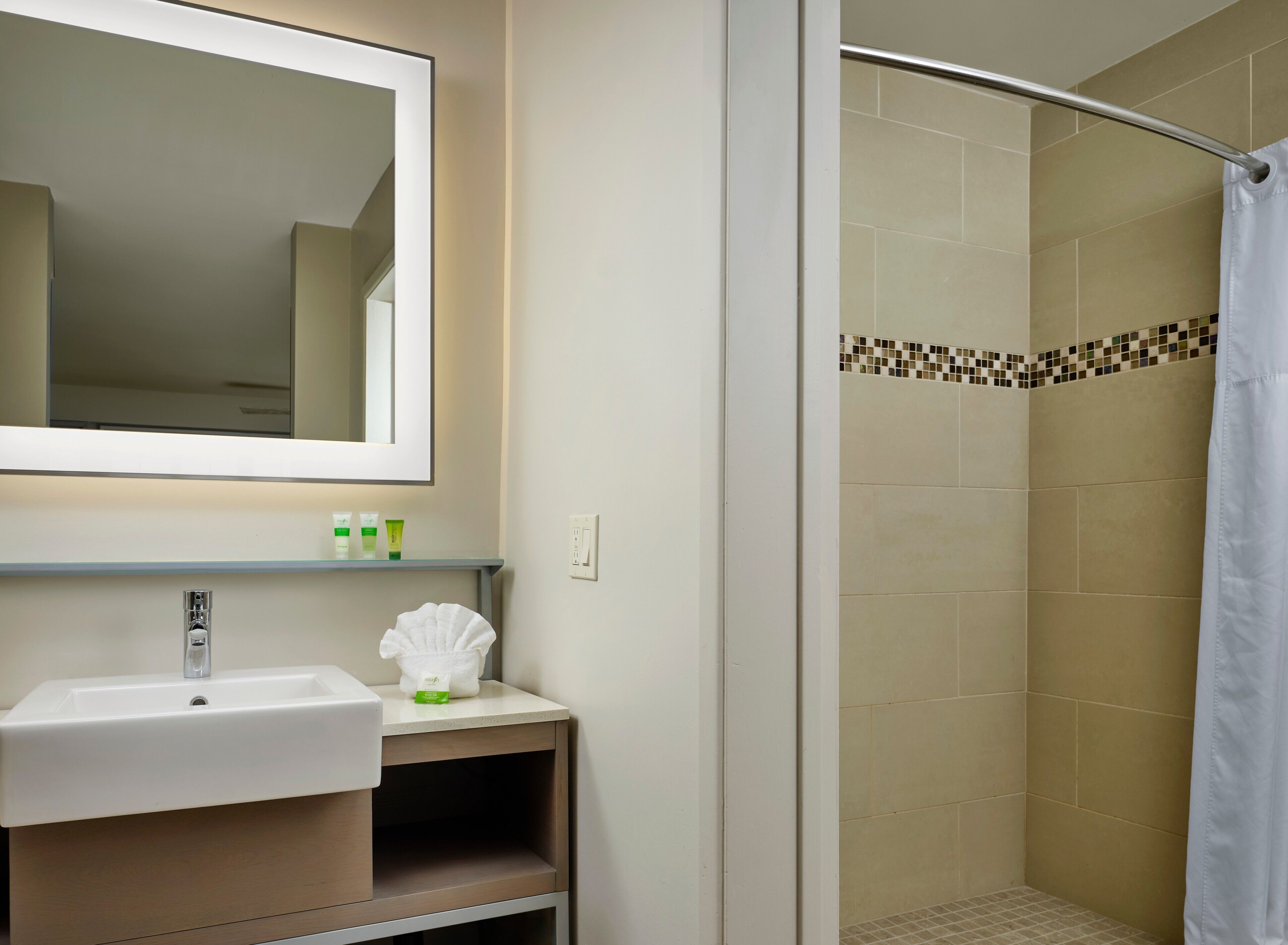 Un baño con lavamanos, espejo y zona de ducha.