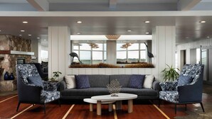 A spacious living area with a gray sofa, two patterned armchairs, a round coffee table, and a stone fireplace.