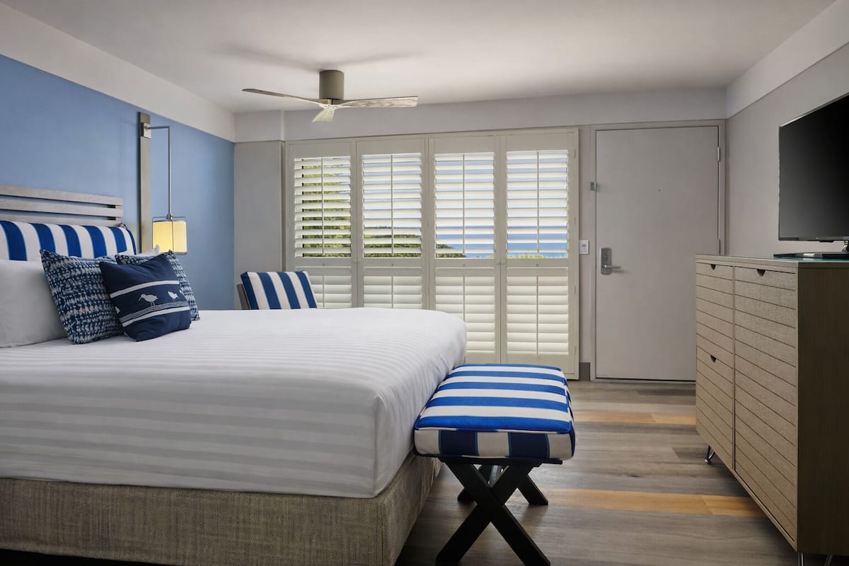 A bedroom with a bed, a bench, a television, and a wardrobe.