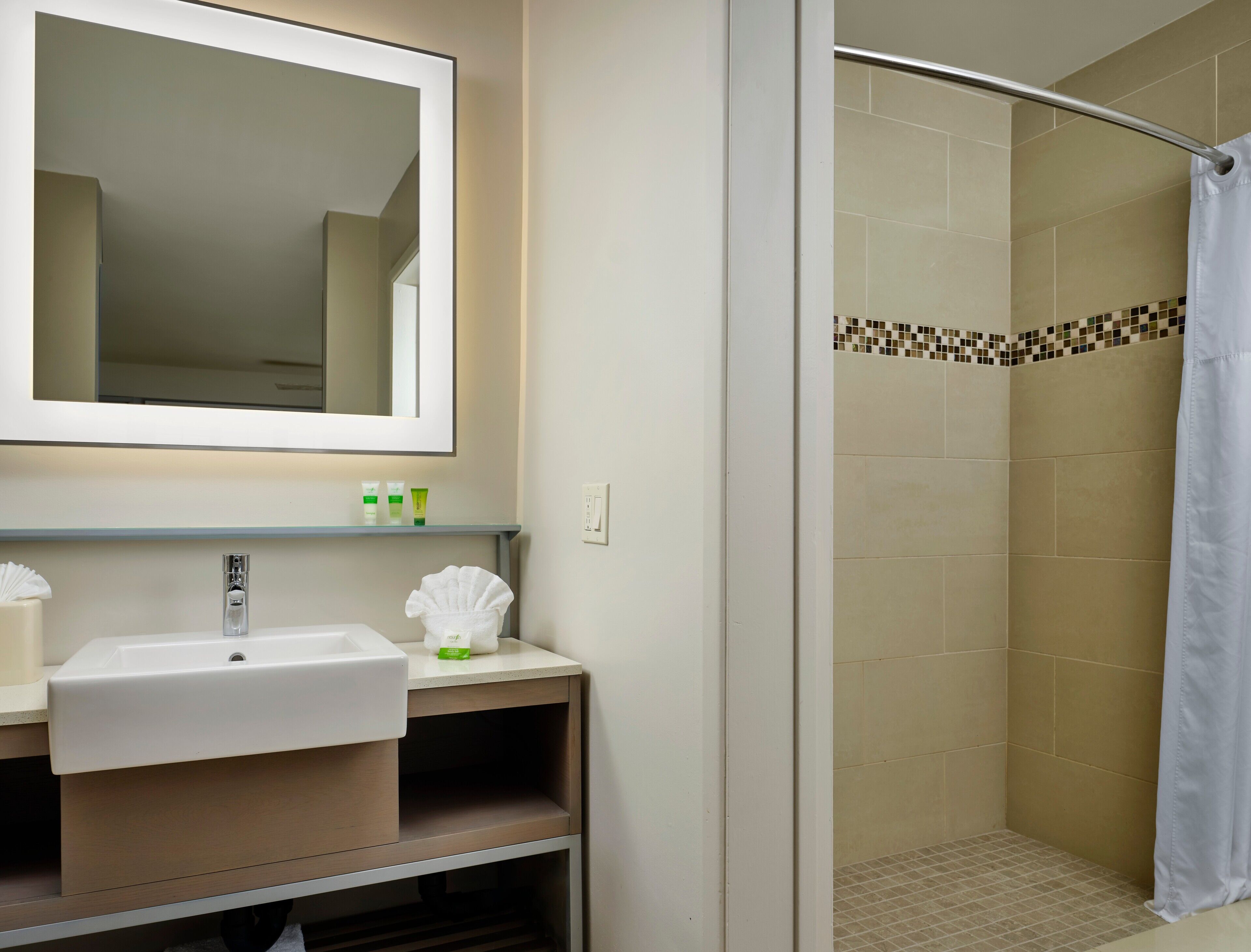 A bathroom with a sink, mirror, and shower.