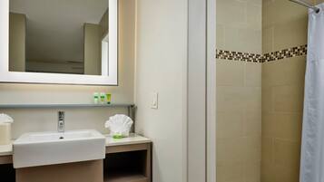 A bathroom with a sink, mirror, and shower.