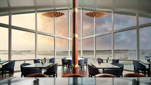 A restaurant with large windows offering a view of the sea and boats.