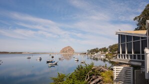 A marina with boats docked, a rocky island in the background, and a building with a balcony overlooking the water.