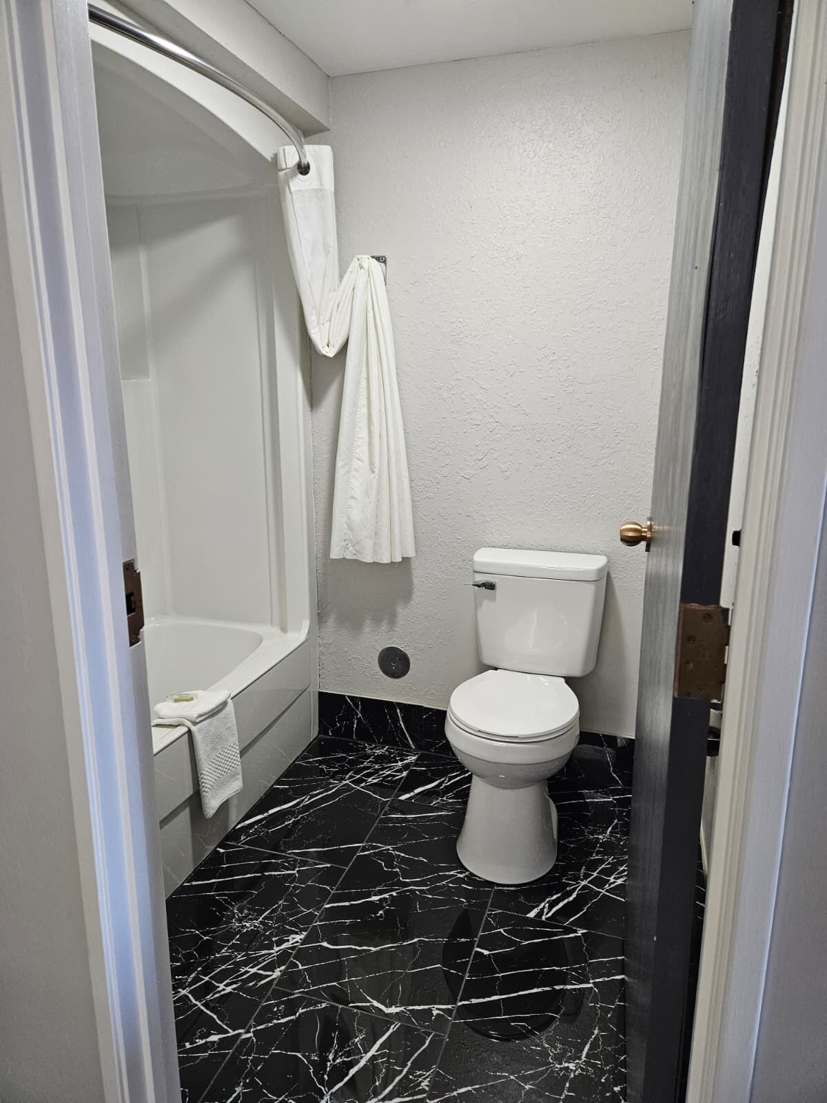 Une salle de bain avec une baignoire, des toilettes et un sol en marbre.