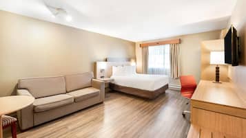 Ein Hotelzimmer mit Bett, einer Couch, einem Schreibtisch und einem Sessel.