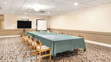 A conference room with a long table, chairs, a TV, and a whiteboard.