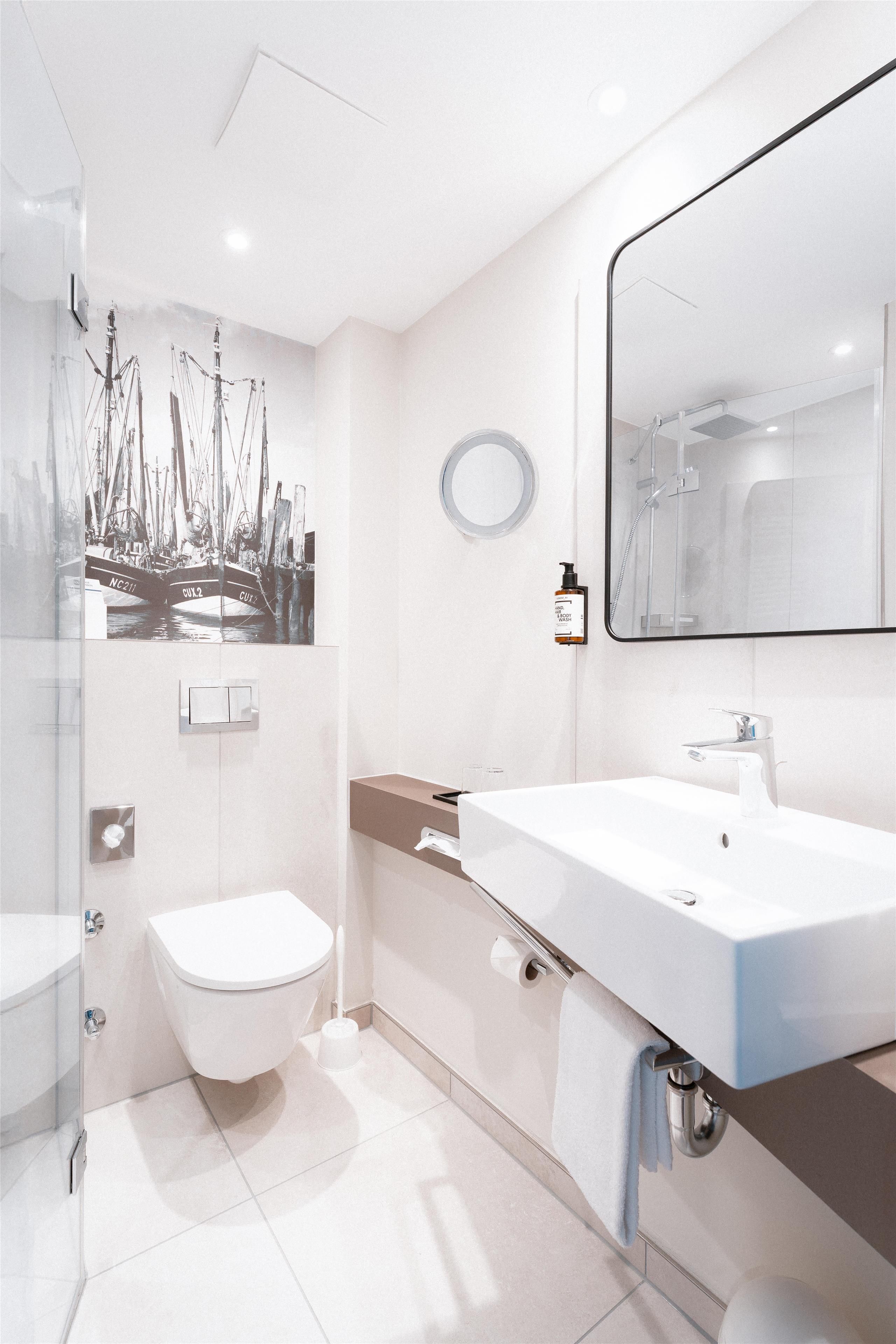 A modern bathroom with a large mirror, a toilet, and a shower area.