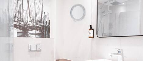 A modern bathroom with a large mirror, a toilet, and a shower area.
