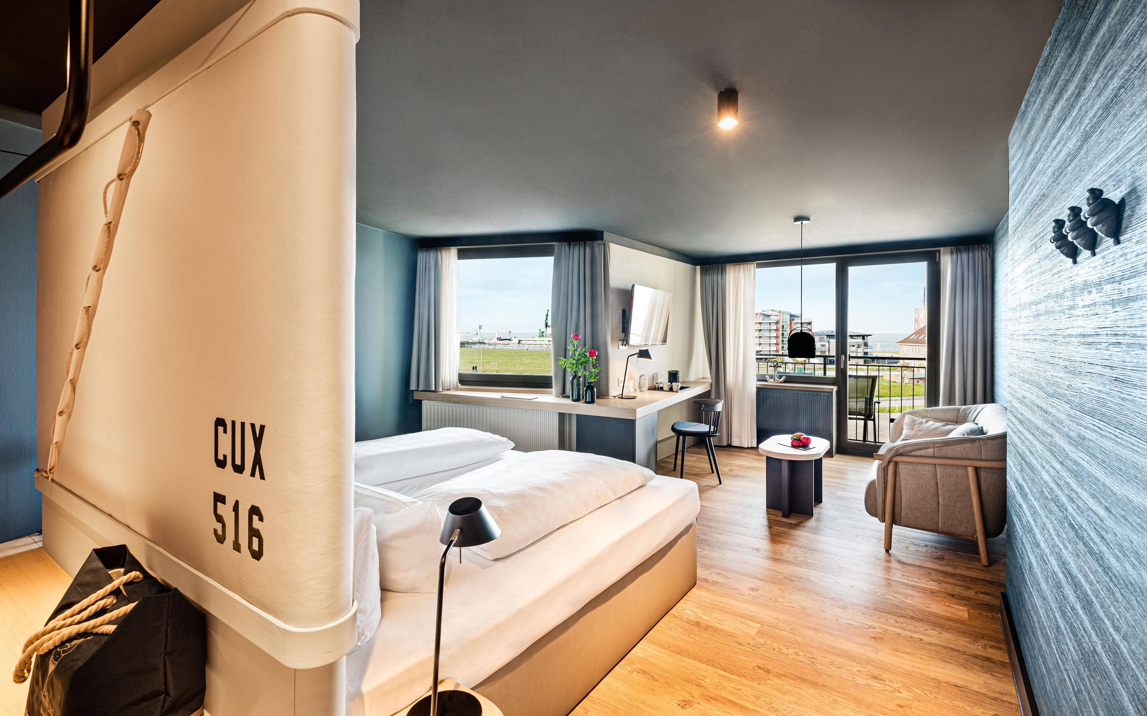 A modern hotel room with a bed, a desk, and a view of the city.