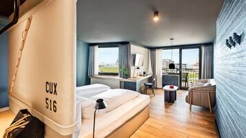 A modern hotel room with a bed, a desk, and a view of the city.