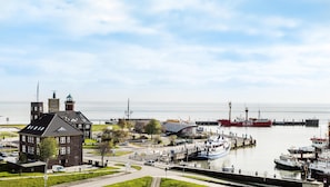 Un puerto con barcos, un faro y un edificio con tejado verde.