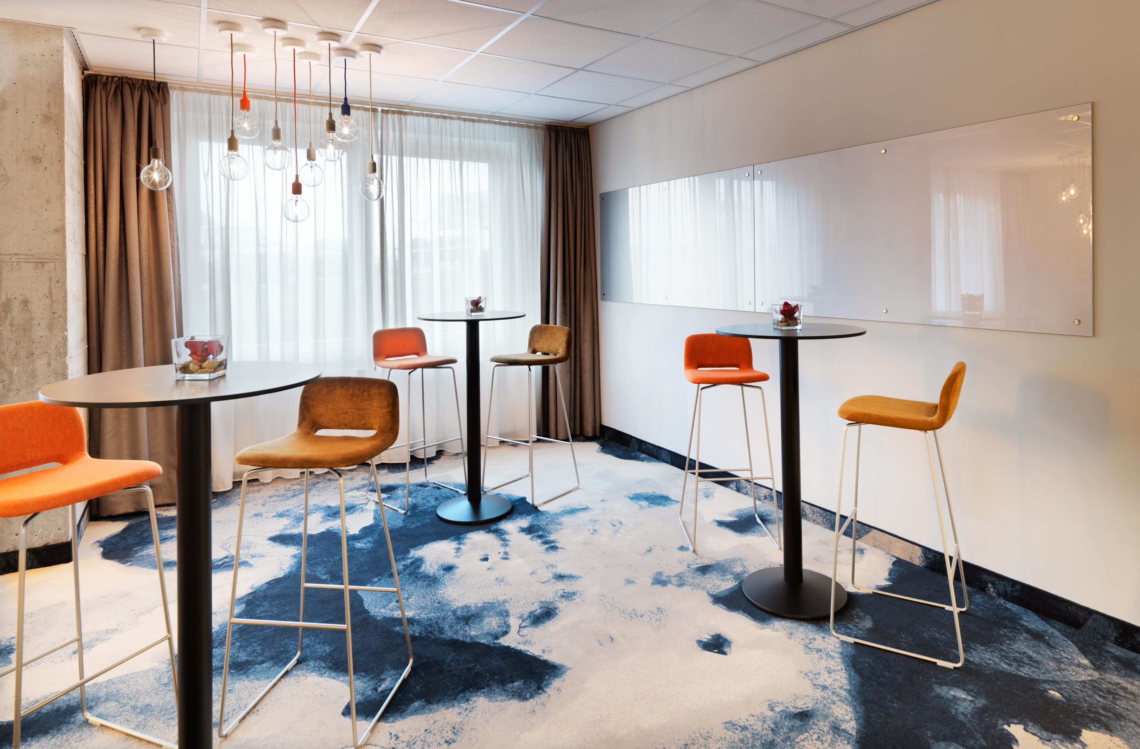 A modern conference room with round tables, chairs, and a large whiteboard.