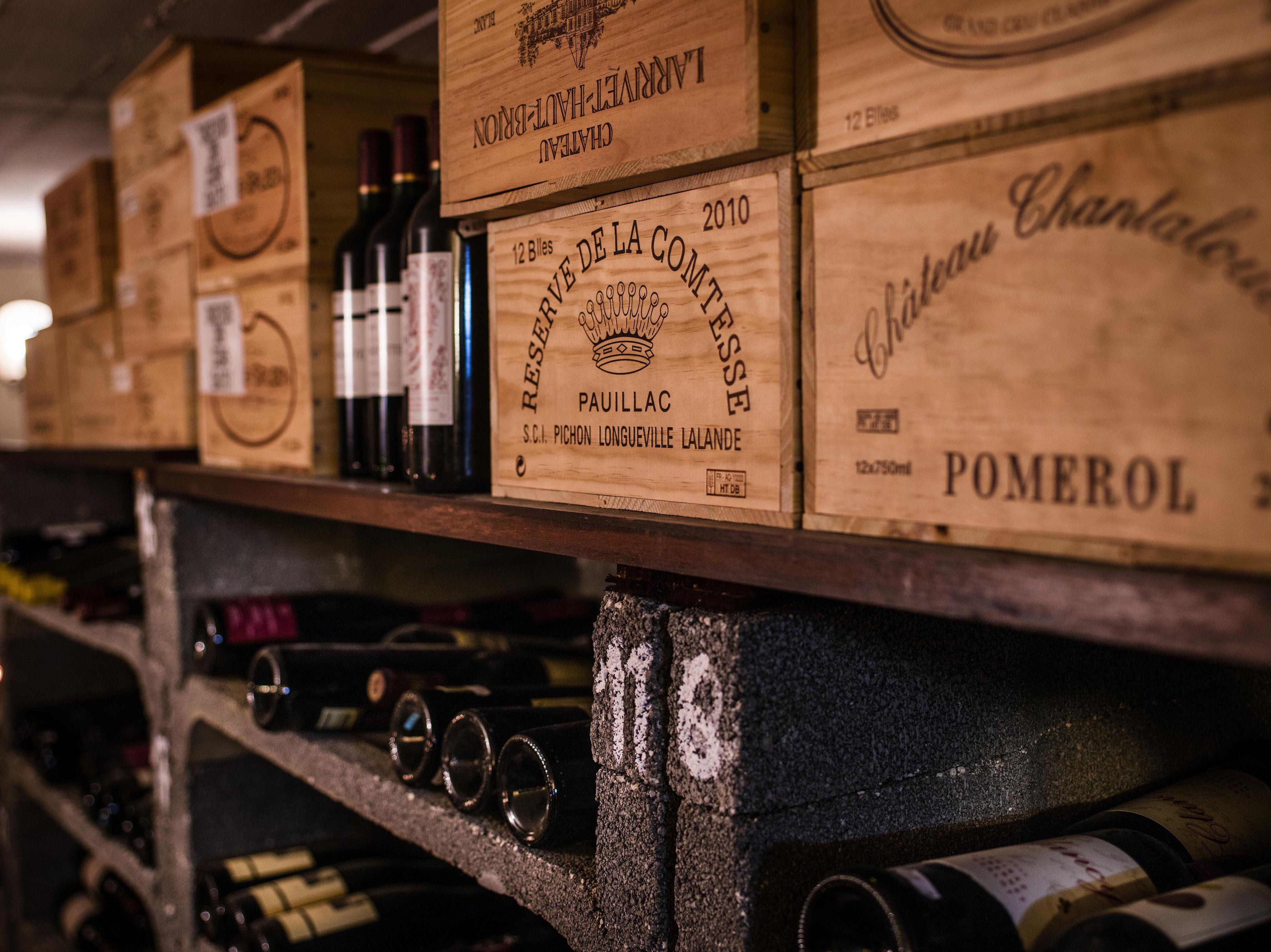 Wooden wine boxes with labels on a shelf, likely in a wine cellar or storage area.