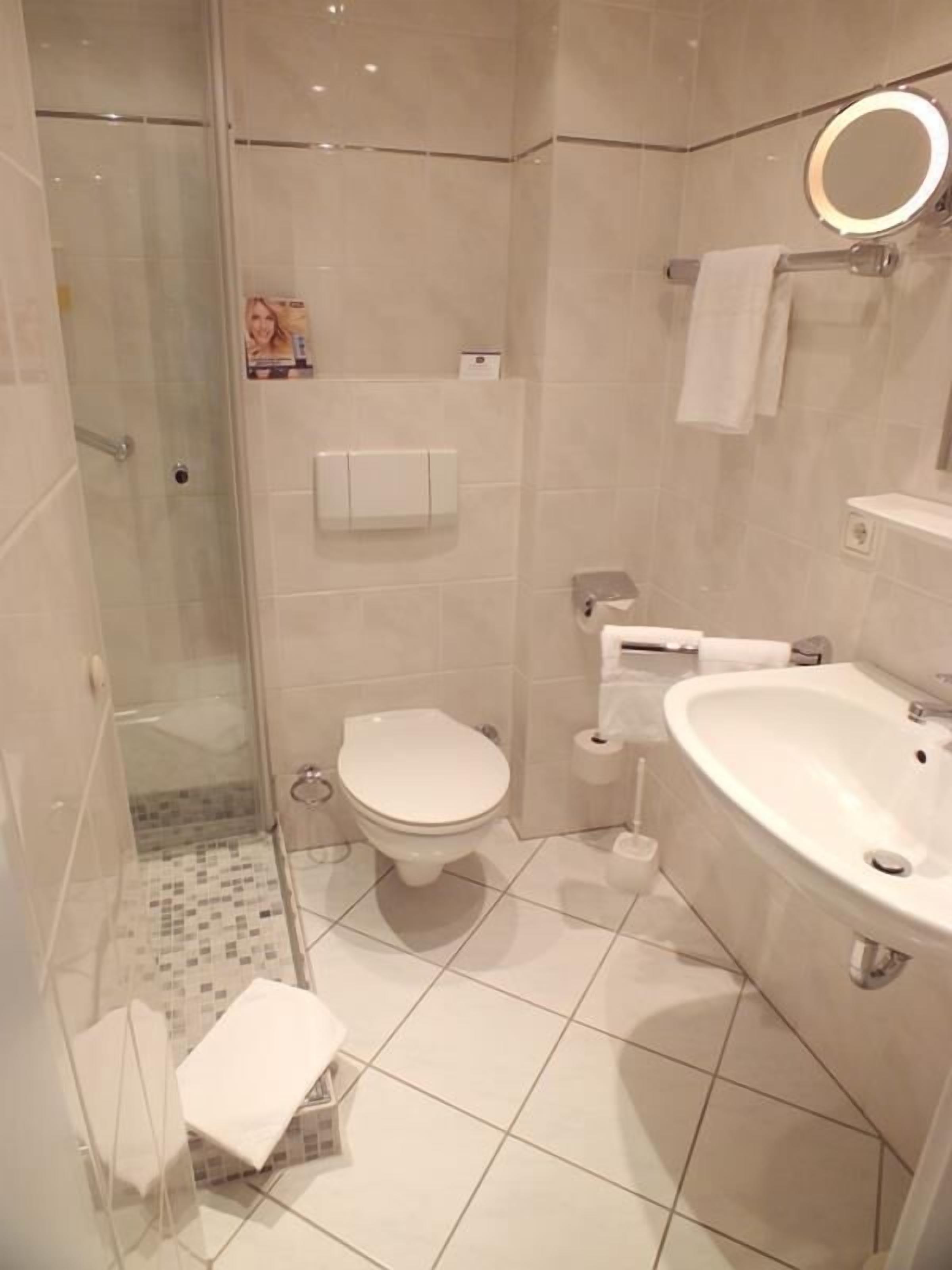 A modern bathroom with a glass shower enclosure, a toilet, a sink, and a towel rack.