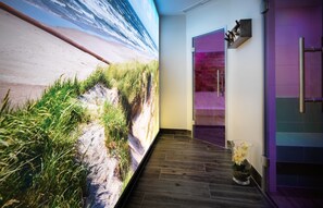 A hallway with a large beach mural, a glass vase with flowers, and a modern bathroom with purple lighting. - Best Western Hotel Das Donners (Cuxhaven)