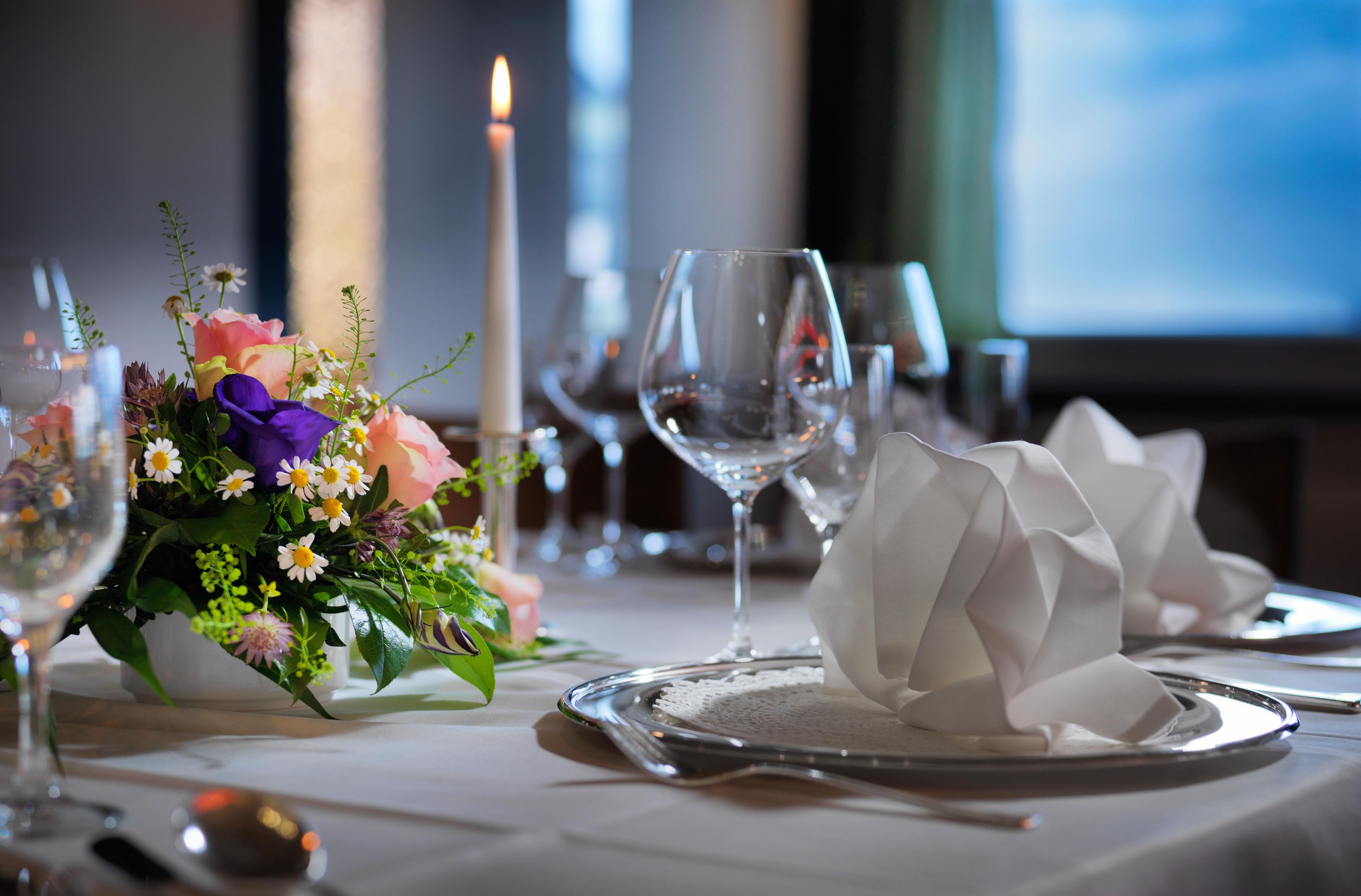 A table set with a candle, a glass of water, and a floral arrangement.