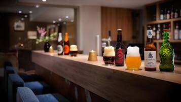 Eine Bar mit verschiedenen Flaschen und Gläsern, einer Kerze und einer grünen Flasche mit rotem Verschluss.