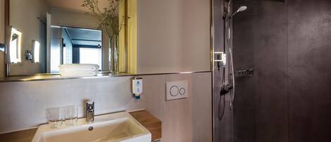 A bathroom with a sink, mirror, shower, and a towel rack.