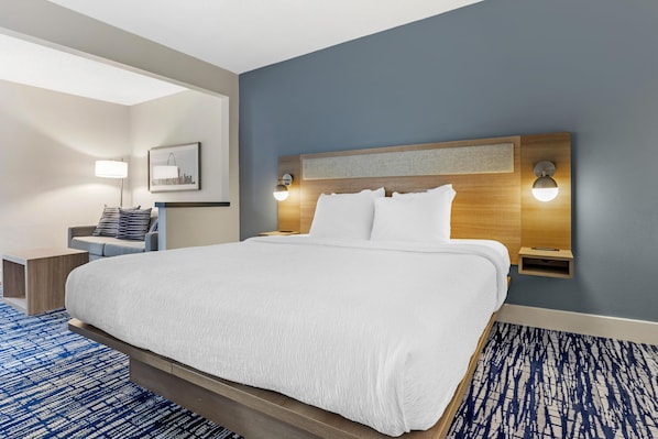 A hotel room with a large bed, a bedside table, a lamp, and a wall-mounted light fixture.