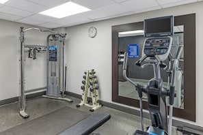 A gym with exercise equipment, a clock, and a digital screen.
