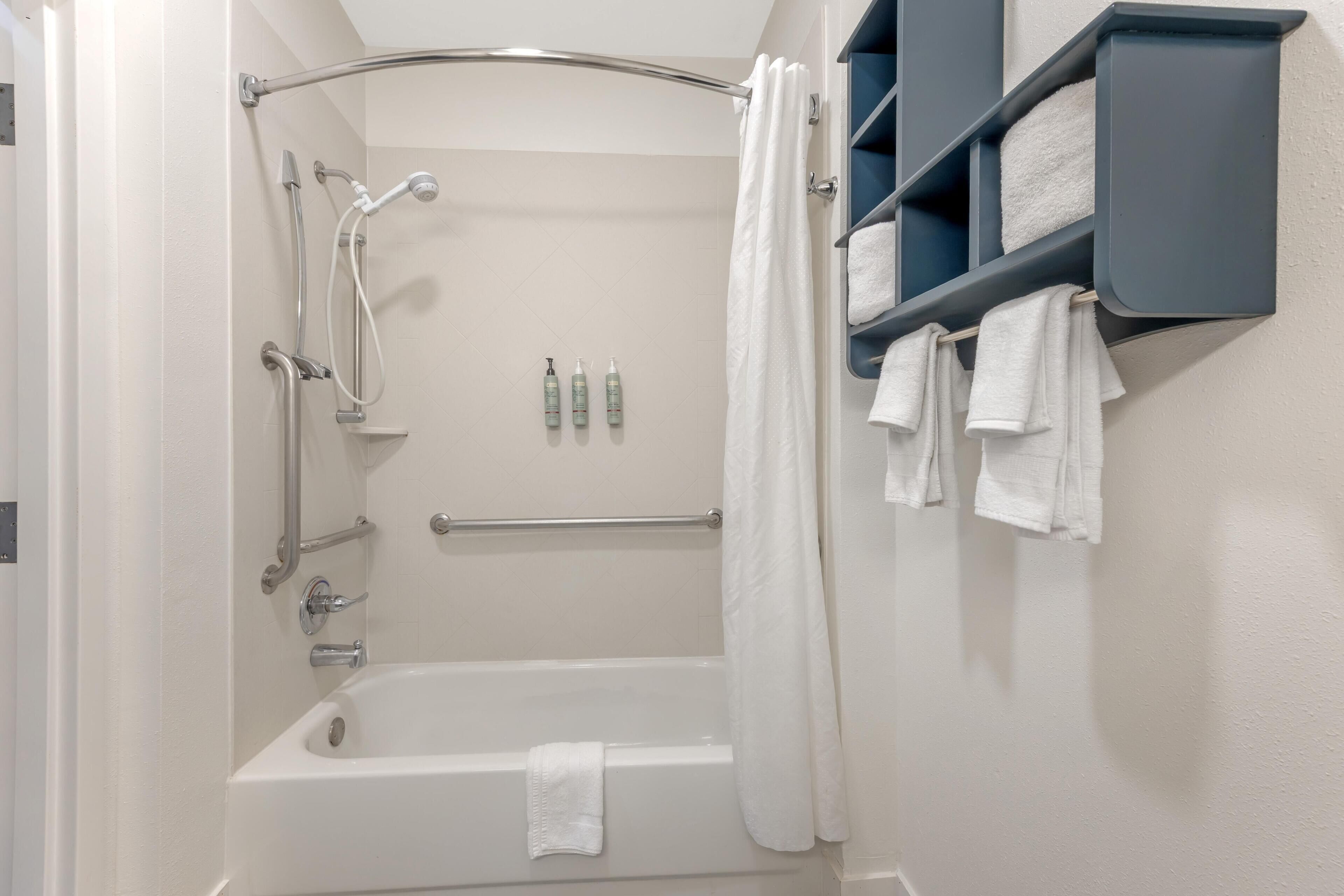 A modern bathroom with a bathtub, shower, and towel rack.