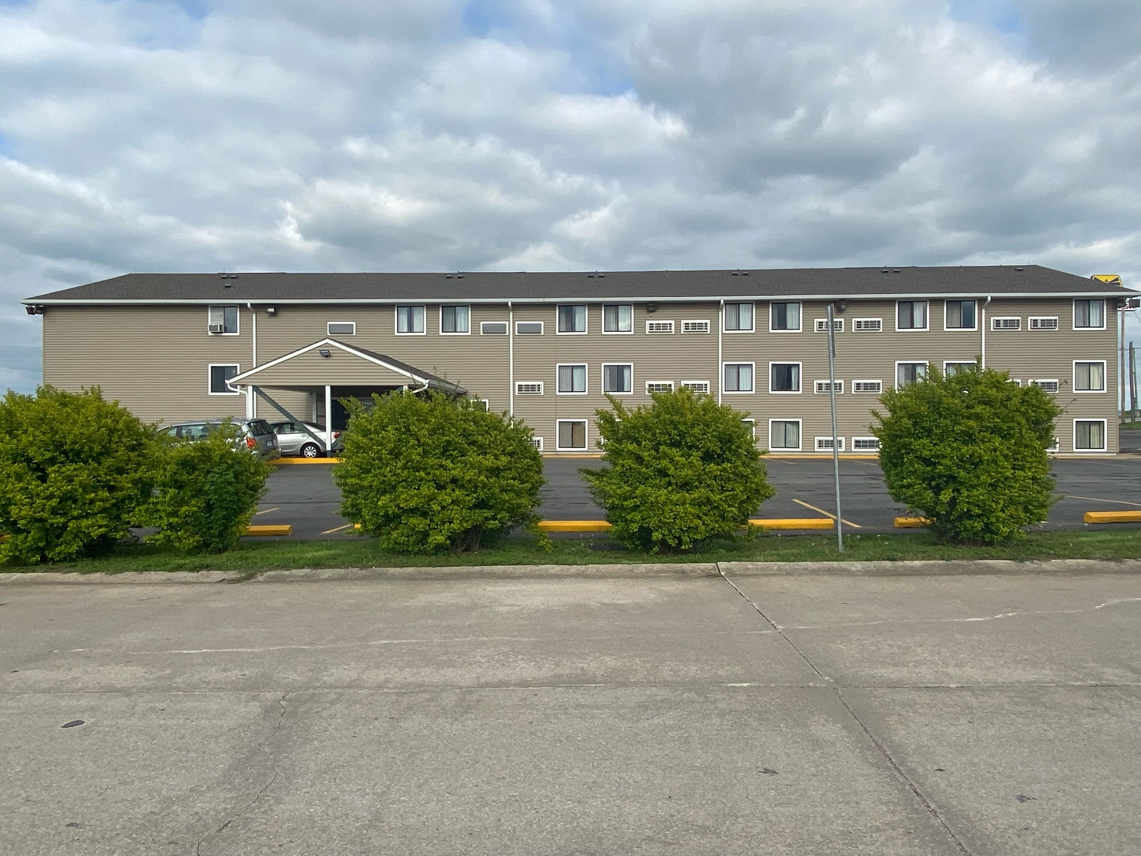Een hotel met meerdere verdiepingen en een parkeerplaats ervoor.