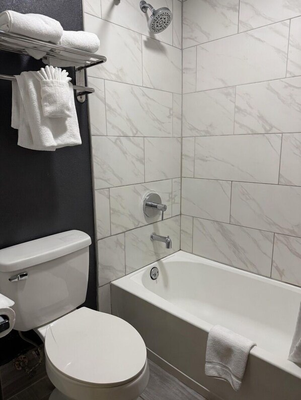 A bathroom with a toilet, bathtub, and shower.