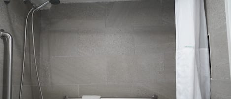 A shower area with a grab bar, a towel rack, and a showerhead.