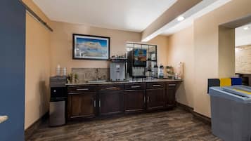 A kitchen with a coffee machine, a water dispenser, and a trash bin.