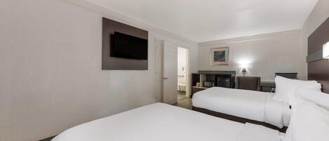 A hotel room with two beds, a flat-screen TV mounted on the wall, a desk with a chair, and a painting on the wall.