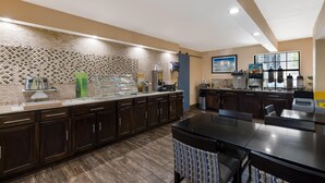 Una cocina moderna con armarios de madera oscura, salpicadero de mármol y una barra desayunadora.