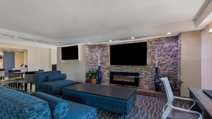 Una sala de estar moderna con sofás de color azul estampados, una chimenea de piedra y un televisor de pantalla plana montado en la pared.