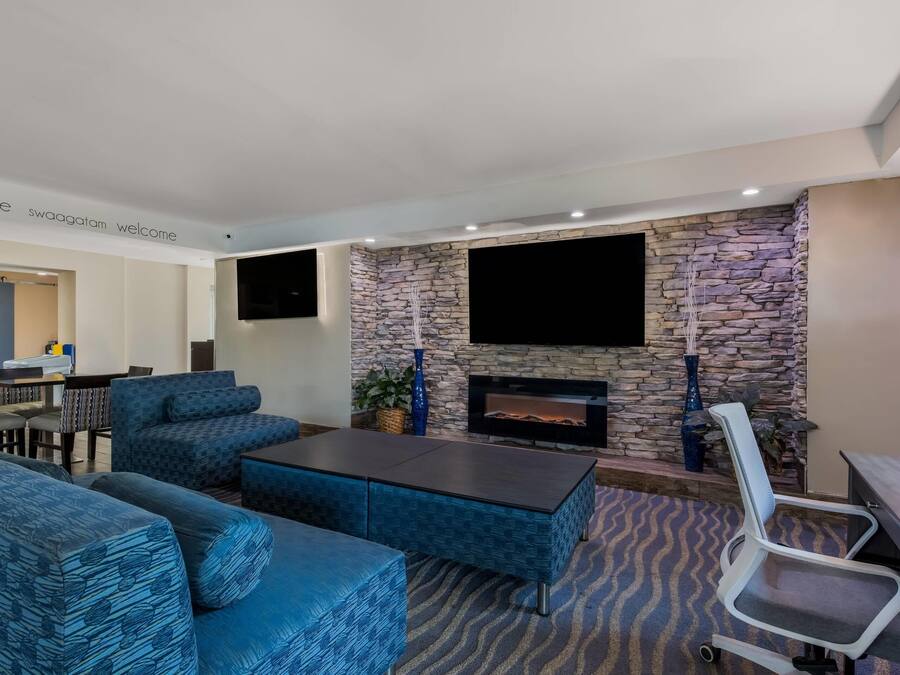 A modern living room with blue patterned sofas, a stone fireplace, and a flat-screen TV mounted on the wall.