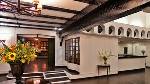 A lobby with a polished wooden floor, a reception desk, and a vase of flowers. - Cresta Churchill (Bulawayo)