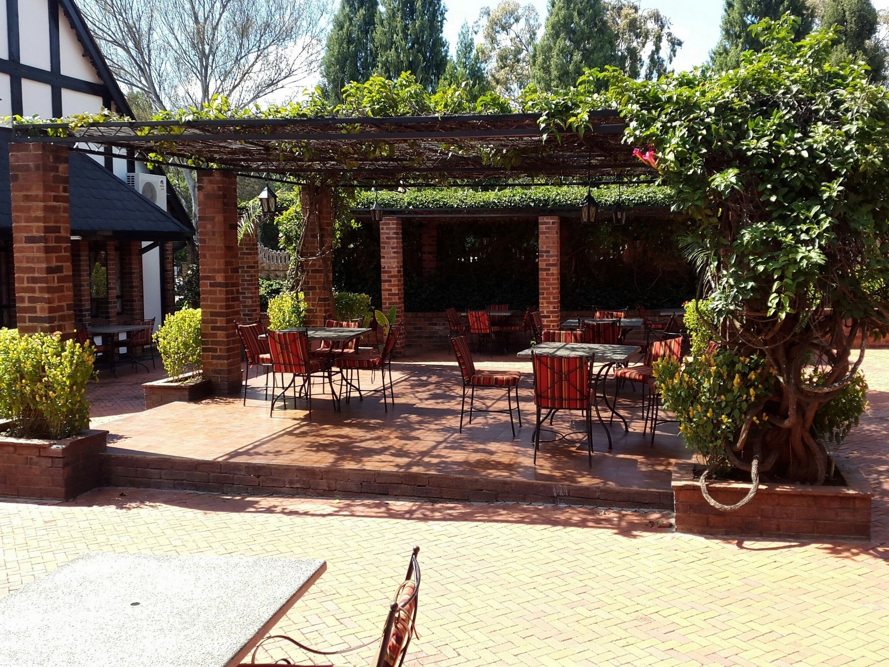 An outdoor patio area with brick flooring, tables, and chairs.