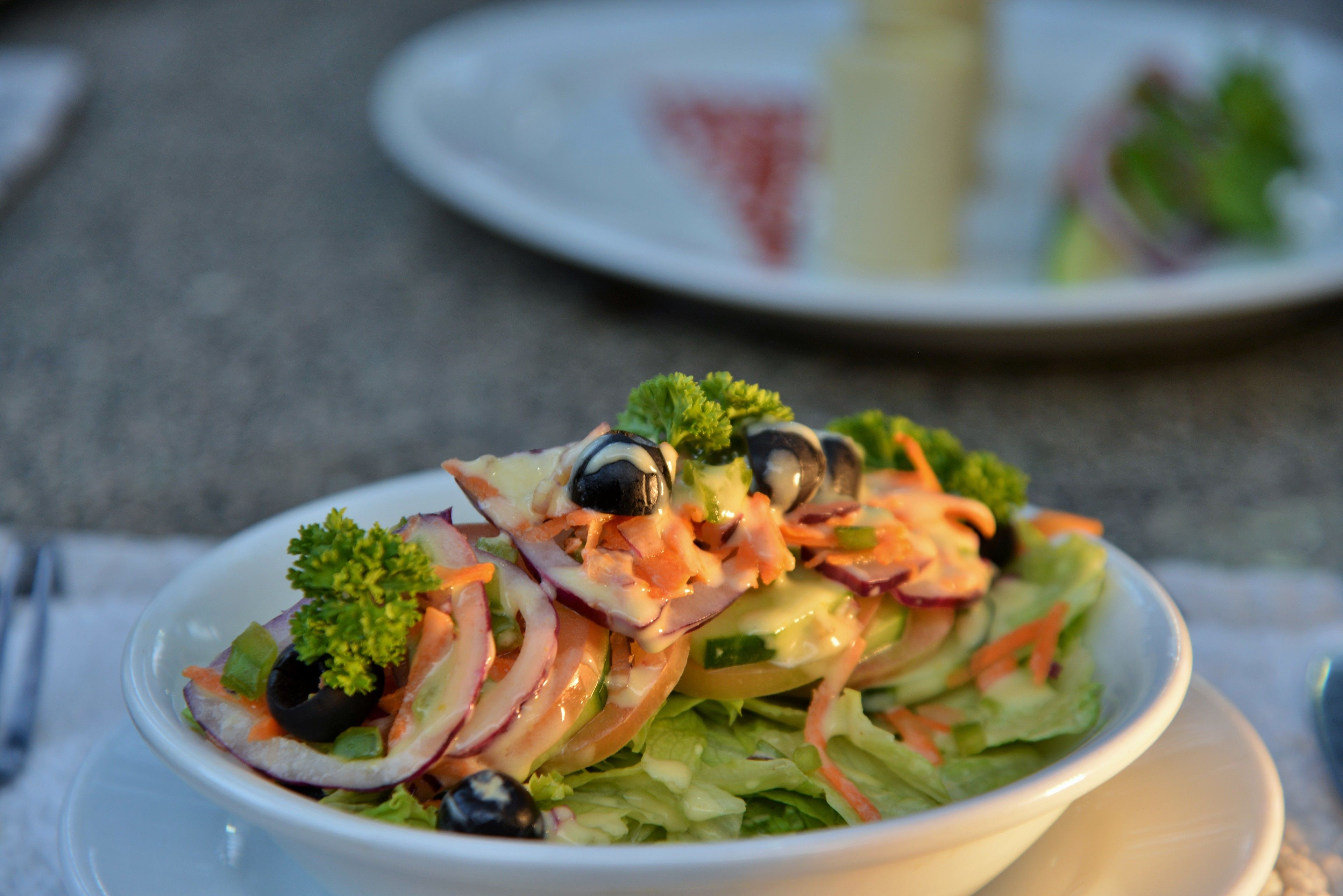 A bowl of salad with various vegetables and a dressing.