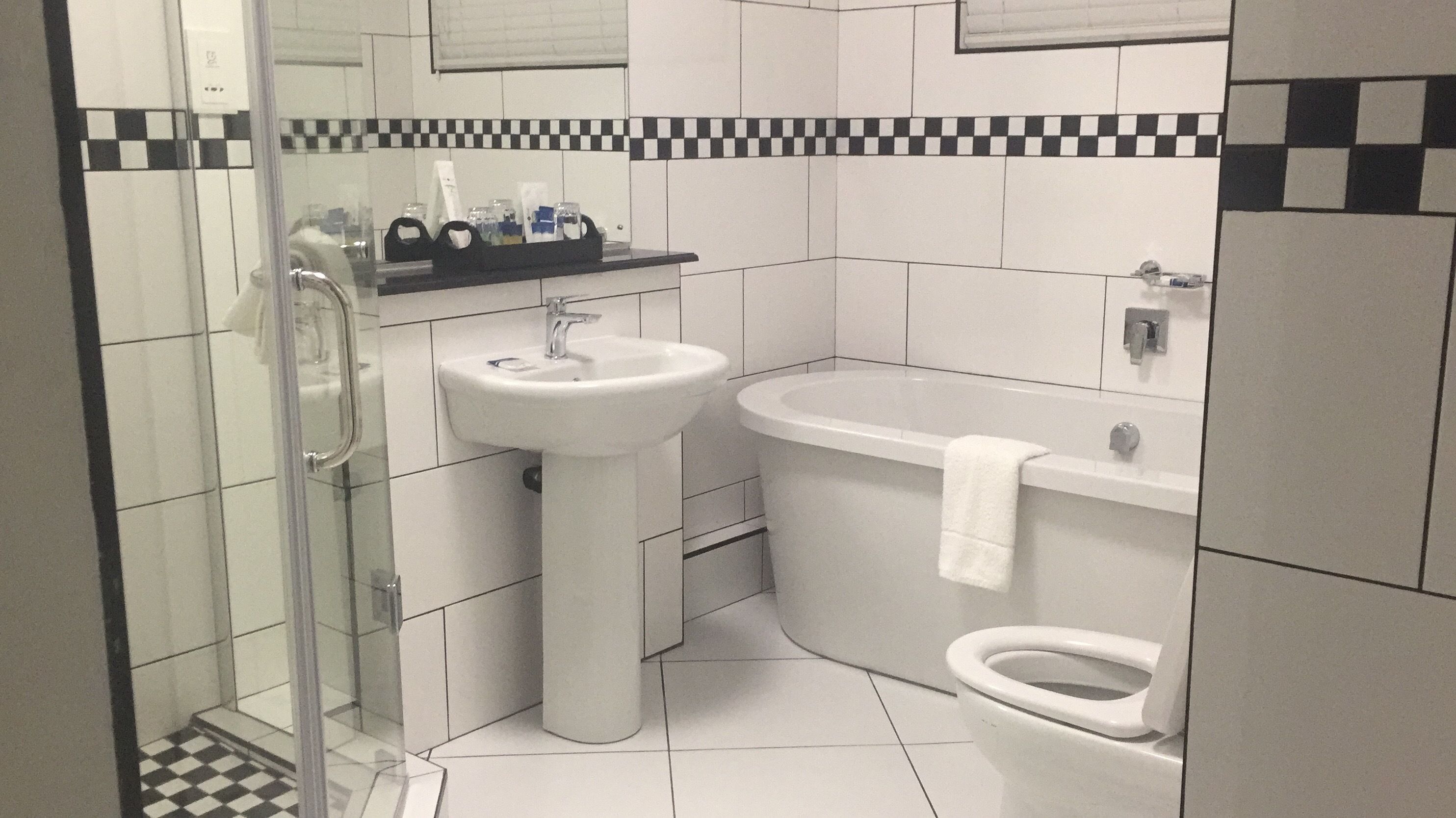 A modern bathroom with a glass shower enclosure, a pedestal sink, a bathtub, and a toilet.