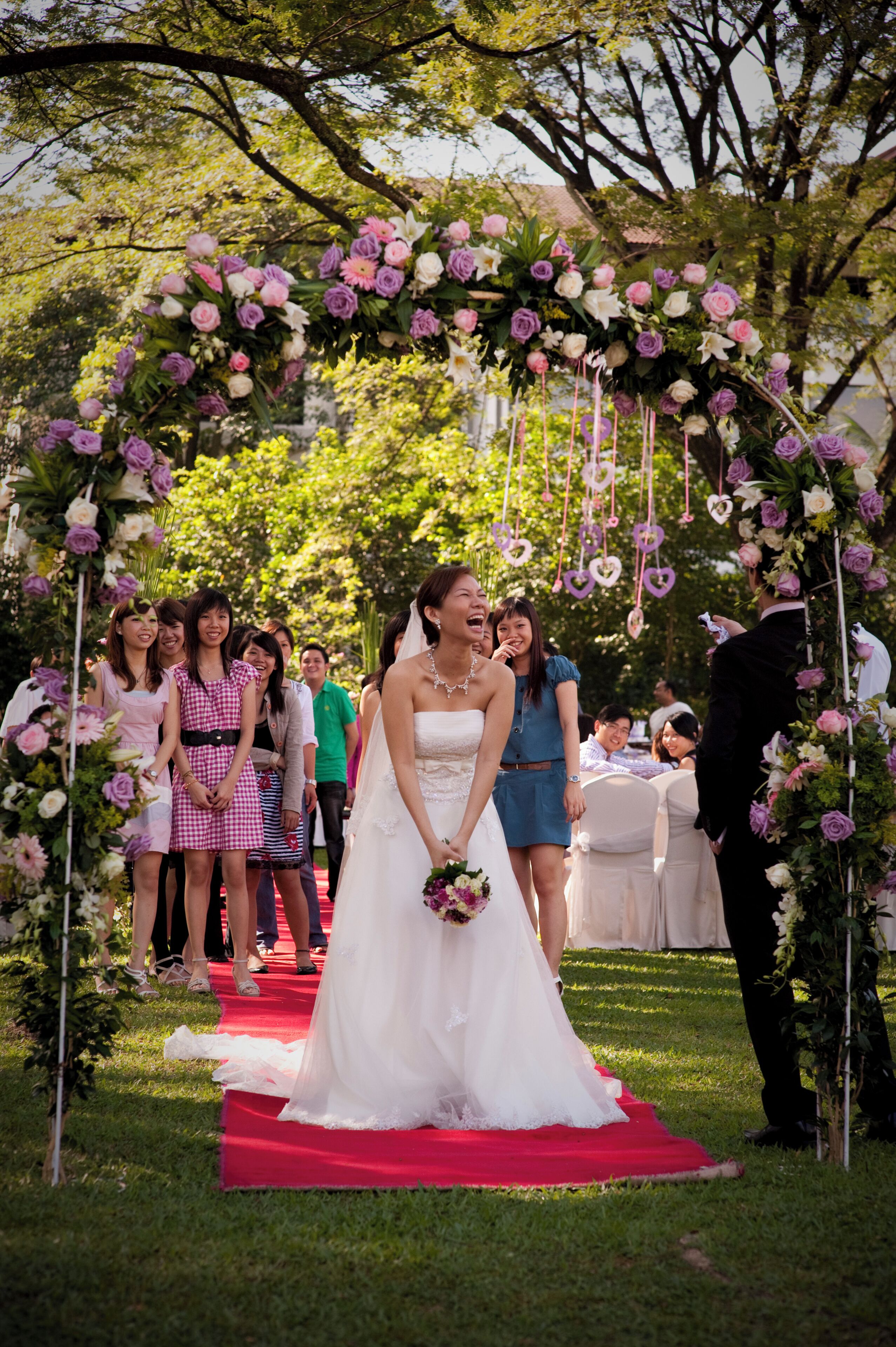 A wedding ceremony with a bride in a white dress, guests, and a red carpet.