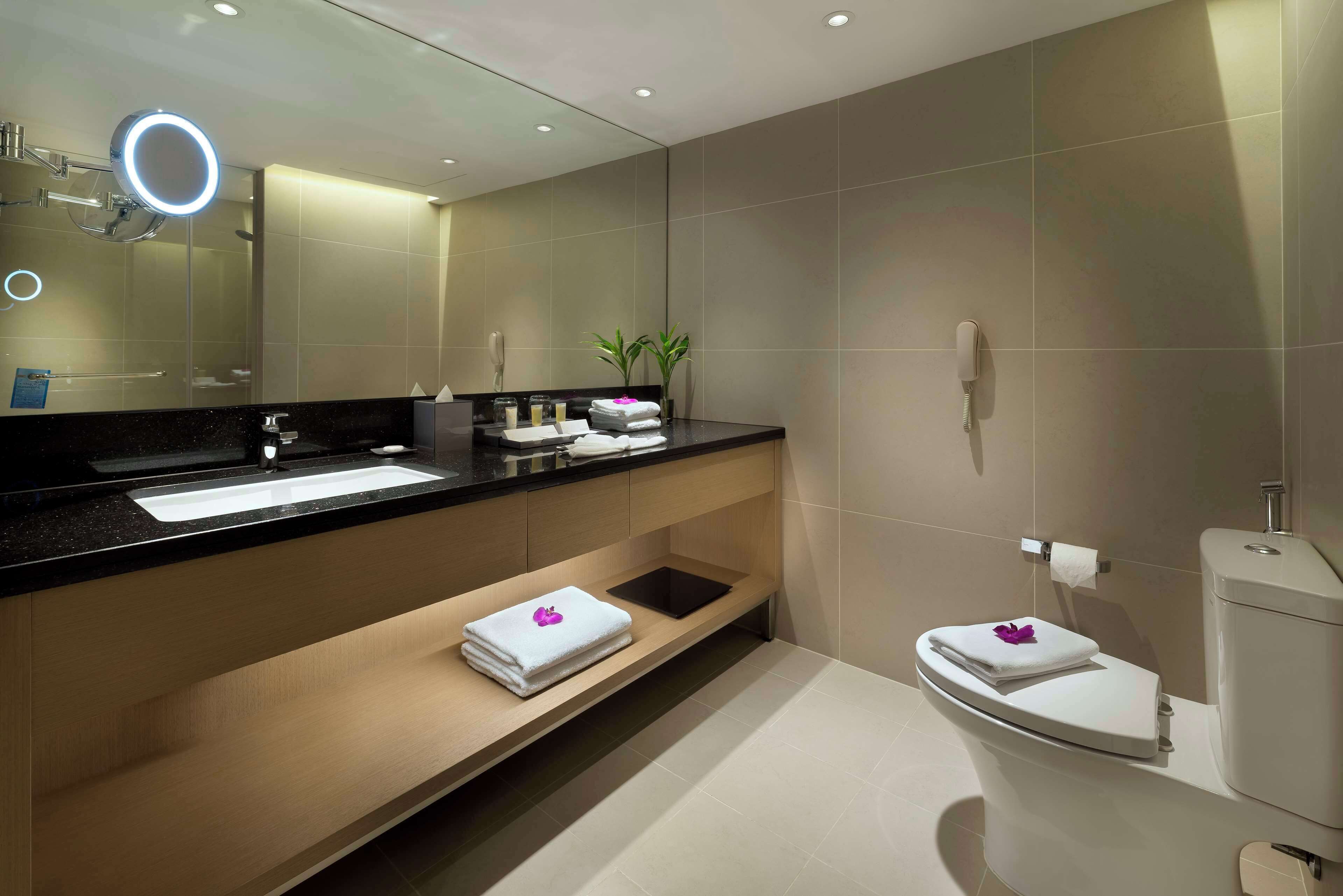 A modern bathroom with a large mirror, a sink, a toilet, and a shower area.