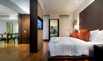 A hotel room with a bed, bedside table, lamp, and a view into the bathroom.