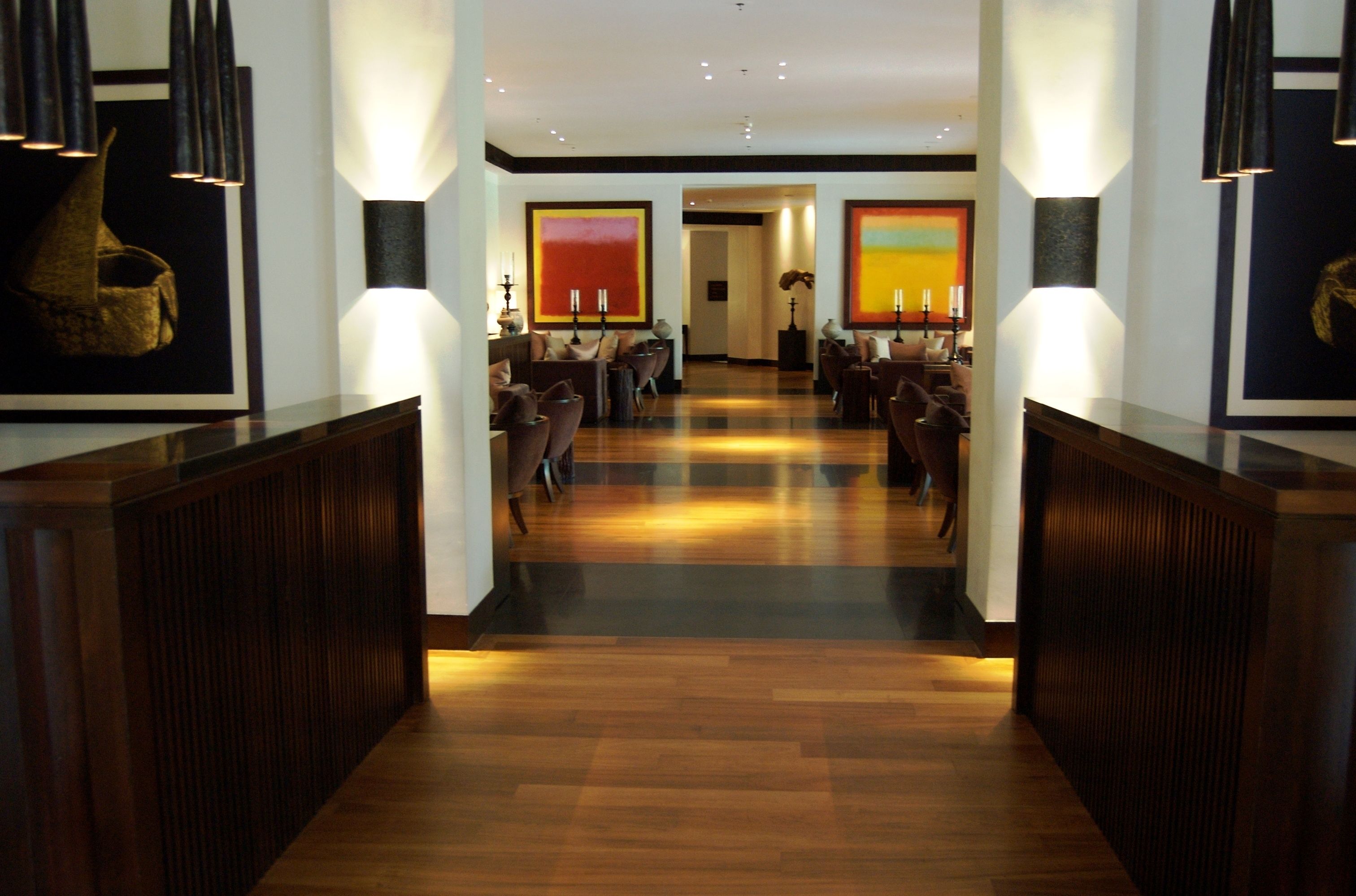 Een hotel lobby met een houten vloer, zithoek en kunstwerken aan de muren.