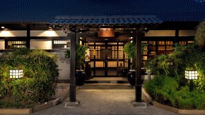 Un edificio de estilo japonés tradicional con techo de tejas, puerta de madera y entrada bien iluminada.