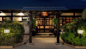 Un edificio de estilo japonés tradicional con techo de tejas, puerta de madera y entrada bien iluminada.