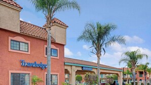 Un hotel Travelodge con una zona de recepción, palmeras y cielo despejado.