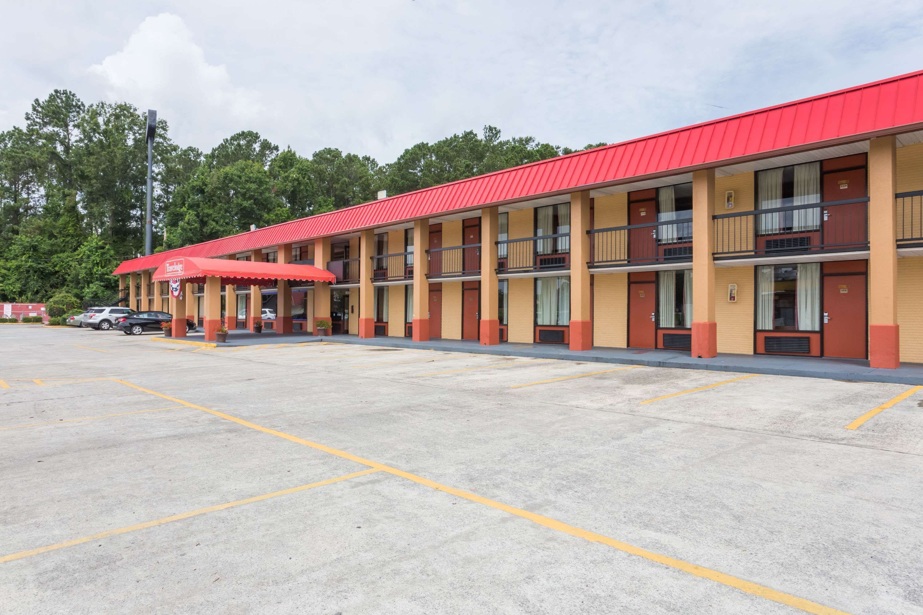 A motel with a red roof and multiple balconies.