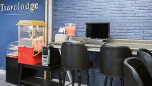 A travel lodge's reception area with a blue brick wall, a popcorn machine, a computer, and bar stools. - Travelodge by Wyndham Savannah Area/Richmond Hill (Richmond Hill)